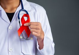 Ein Arzt hält eine rote Aids-Schleife in der Hand. Foto: jcomp/freepik.com