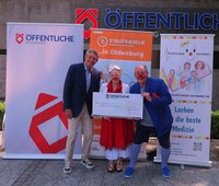 Christian Bunk, Vertriebsdirektor Öffentliche Versicherungen, überreicht den Scheck für das siebte Etappenziel an zwei Klinikclowns. Foto: Stadt Oldenburg Christian Bunk, Vertriebsdirektor Öffentliche Versicherungen, überreicht den Scheck für das siebte Etappenziel an zwei Klinikclowns. Foto: Stadt Oldenburg