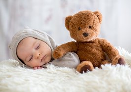 Baby schläft neben Teddy. Foto: Tomsickova/Adobe Stock