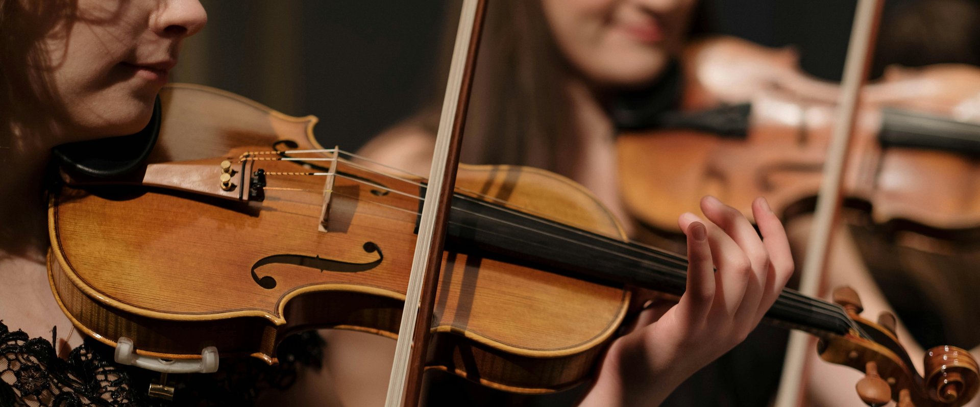 Frauen spielen auf Geigen. Foto: Pexels