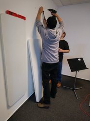 Zwei Kollegen der Musikschule schrauben Absorberplatten an die Wand. Foto: Stadt Oldenburg