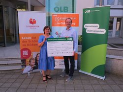 Holger Sandker, stellvertretender Vorstandsvorsitzender der OLB-Stiftung, überreicht den Scheck für das erste Etappenziel an Daniela Pfeiffer, Vorstandsvorsitzende von Mentor Oldenburg. Foto: Stadt Oldenburg 