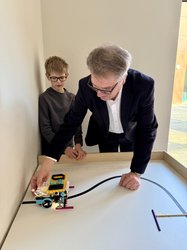 Oberbürgermeister Jürgen Krogmann testet einen kleinen selbstprogrammierten Intech-Roboter, der von Schülern in der Informatik-AG entwickelt wurde. Foto: Stadt Oldenburg