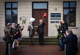 Vor dem Standesamt stehen zwei Männer mit Herzluftballons in den Händen. Davor stehen Menschen mit Rosen in den Händen Spalier. Foto: Alexander Rumyantsev
