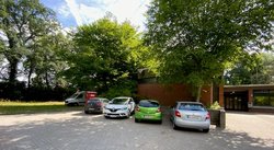 Gemeindezentrum mit Parkplatz und Autos