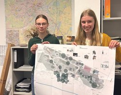Janne und Paula haben ihren Zukunftstag in den Bereichen Repräsentation und Pressebüro verbracht. Dabei besuchten sie den Fachdienst Stadtgrün – Planung und Neubau, um eine Reportage und eine Rede zu schreiben. Foto: Stadt Oldenburg Janne und Paula mit einer großen Karte vor einem großen Plan der Stadt Oldenburg. Foto: Stadt Oldenburg