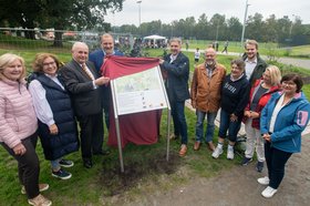 Oberbürgermeister Krogmann (rechts an der Tafel) enthüllte mit Vertreterinnen und Vertretern aus Politik, Verwaltung, Sanierungsbeirat und dem Bürgerverein Bümmerstede/Kreyenbrück die Übersichtstafel für den Sportpark Kreyenbrück. Foto: Sascha Stüber