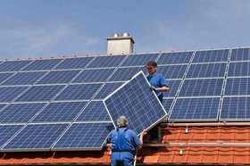 Zwei Handwerker bringen Solarmodul auf Hausdach. Foto: Marina Lohrbach / Adobe Stock