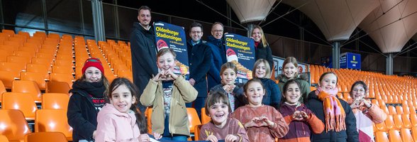 Freuen sich auf das Stadionsingen: (hinten, von links) Marco Harms (Sportbüro der Stadt Oldenburg), Dimitri Melnik (Leiter der Musikschule), Christian Köhler (Vorsitzender der Regionalen Stiftung der LzO) und Chantal Cordes (Kinderchor-Leiterin) sowie einige der Chorkinder. Foto: Sascha Stüber 