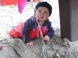 Kind im Sand an einem Wasserspielzeug. Foto: Stadt Oldenburg