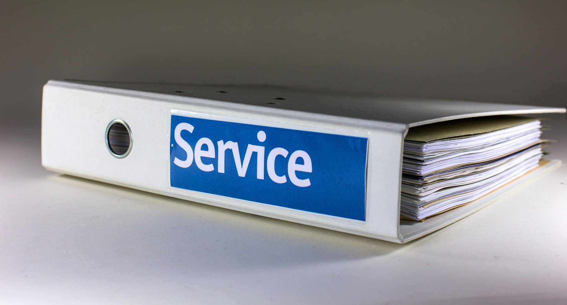 Weißer Ordner liegt auf der Seite. Auf blauem Aufkleber steht „Service“. Foto: Rainer Sturm/Pixelio.de