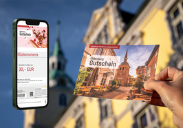 Oldenburg Gutschein wird vor das Oldenburger Schloss gehalten sowie links der Oldenburg Gutschein auf einem Handy. Foto: OTM/Henricus Lüschen