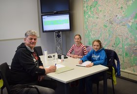 Valentina und Martha mit Thomas Hanauer an einem Tisch, im Hintergrund eine große Oldenburg-Karte mit Lichtern. Foto: Ben