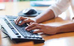 Hände tippen auf einer Computer-Tastatur. Foto: Syda Productions/AdobeStock