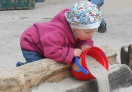 Ein Kind spielt mit einem Eimer im Sand. Foto: Stadt Oldenburg