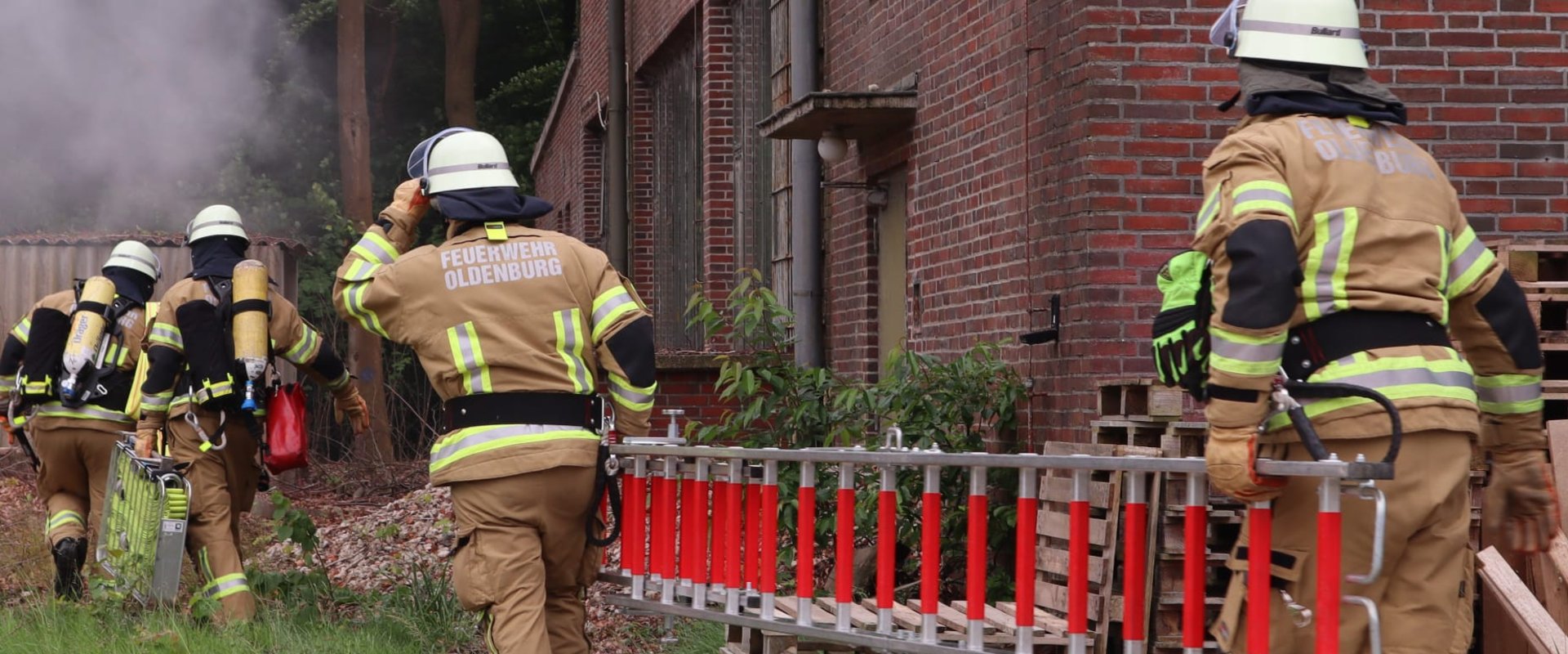 Zwei Kameraden der Feuerwehr tragen eine Leiter zu einem brennenden Haus. Foto: Feuerwehr Oldenburg