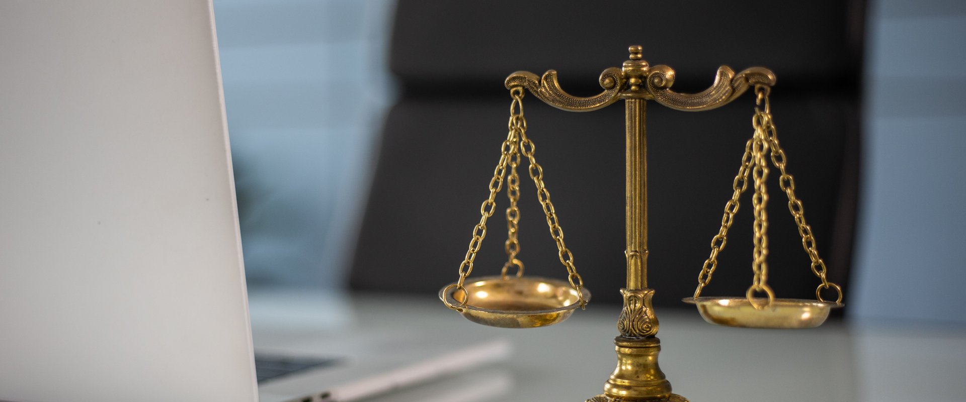 Kleine goldene Waage auf einem Schreibtisch neben einem Laptop. Foto: ekaterina-bolovtsova/pexels 