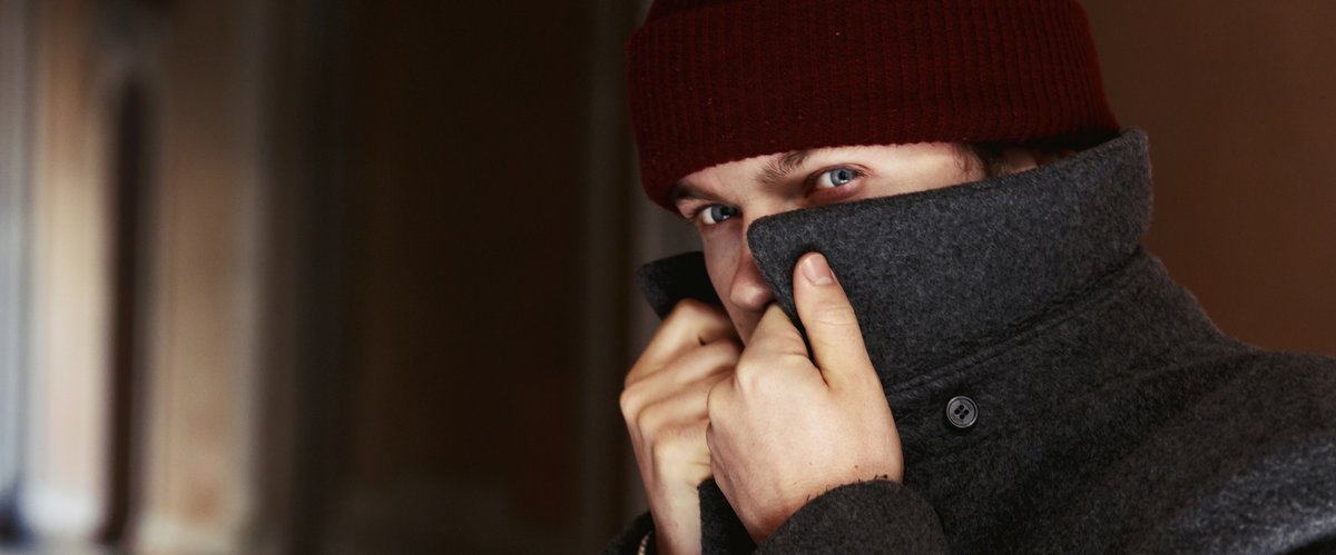 Ein Mann verdeckt sein Gesicht mit seinem Mantel. Bild: Freepik/freepic.diller