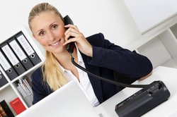Symbolbild: Telefonierende Frau vor einem Laptop am Schreibtisch sitzend. Foto: Tim Reckmann/Pixelio.de