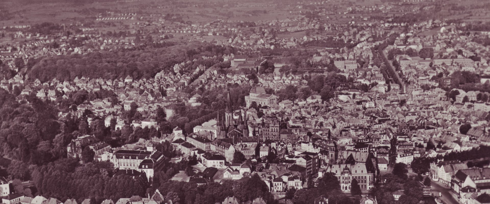 Luftbild aus den 1950er Jahren von der Stadt Oldenburg mit Blick auf die Innenstadt mit Lambertikirche, Rathaus, Schloss, Postgebäude und Stau, vorn die Amalienstraße, im Hintergrund das Gebäude des Verwaltungsbezirks Oldenburg, von Osten aus