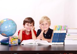 Zwei Schulkinder mit Globus und Büchern. Foto: Kris/Pixabay