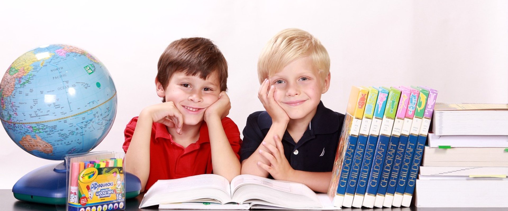 Zwei Schulkinder mit Globus und Büchern. Foto: Kris/Pixabay