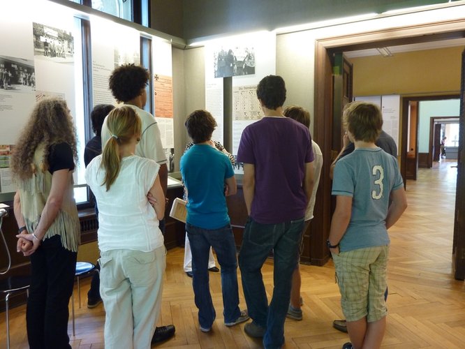 Jugendliche betrachten ein Poster an einer Wand. Foto: Stadt Oldenburg