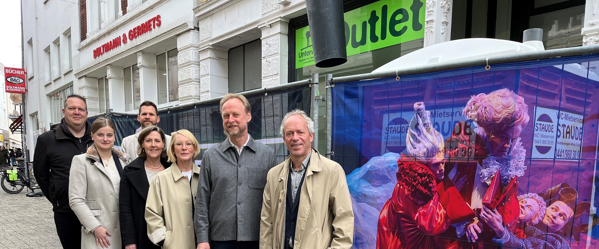 Ralph Wilken (rechts, Leiter Wirtschaftsförderung), mit Beteiligten der Wirtschaftsförderung, des Staatstheaters und des Theaterquartiers beim Auftakt in der Gaststraße – die Bauzaunbanner verbinden Stadtentwicklung und Kultur. Foto: Stadt Oldenburg
