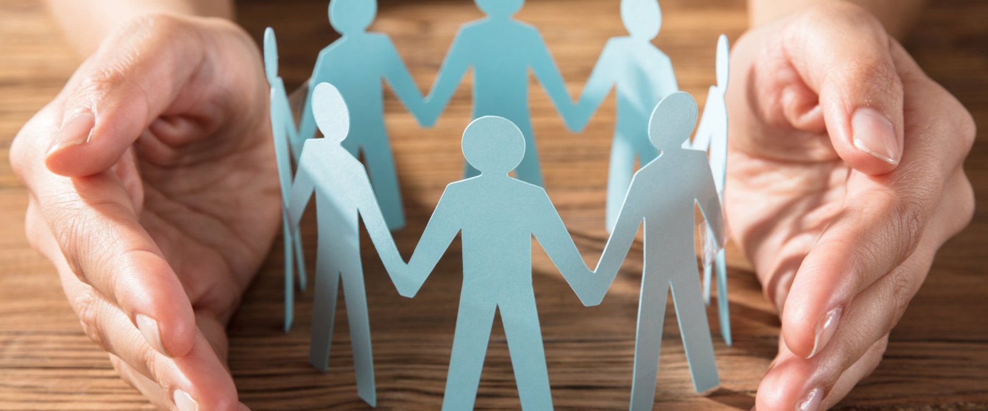 Ein Kreis aus Papierfiguren wird von zwei Händen geschützt. Foto: Andrey Popov/AdobeStock