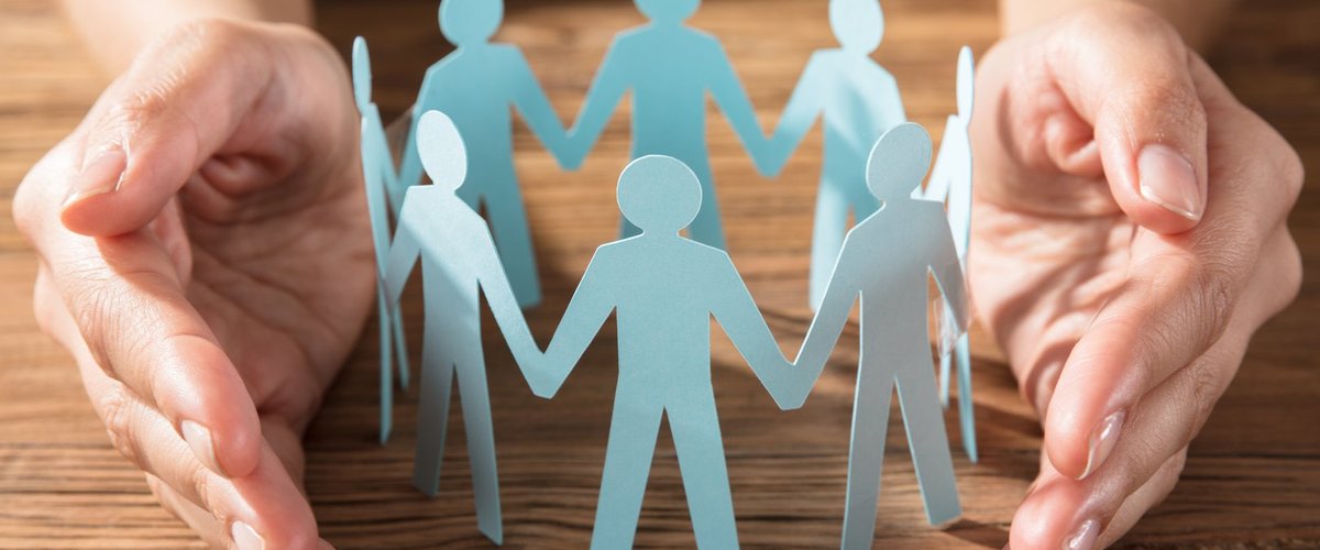 Ein Kreis aus Papierfiguren wird von zwei Händen geschützt. Foto: Andrey Popov/AdobeStock