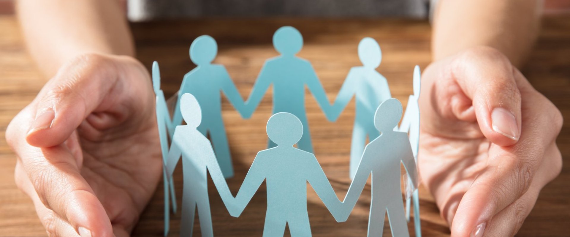 Ein Kreis aus Papierfiguren wird von zwei Händen geschützt. Foto: Andrey Popov/AdobeStock