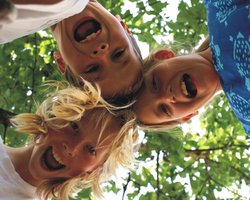 Drei lachende Kinder stehen im Kreis. Foto: S. Hofschlaeger/Pixelio
