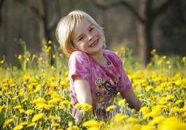 Lachendes Mädchen in einer gelben Blumenwiese. Foto: anschi/Pixelio