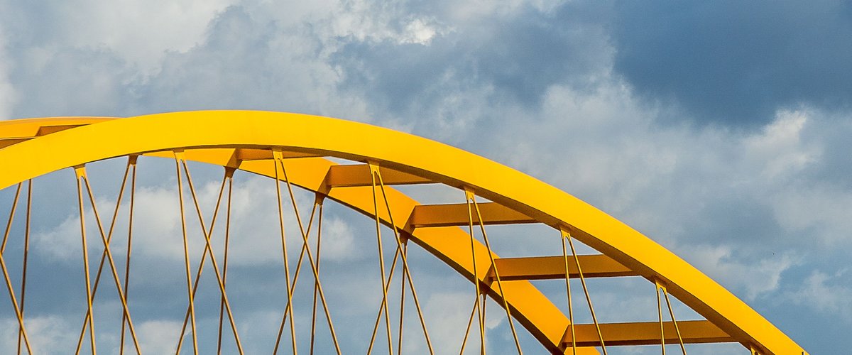 Gelber Stahlbogen einer Brücke. Foto: Mike van Schoonderwalt/Pexels