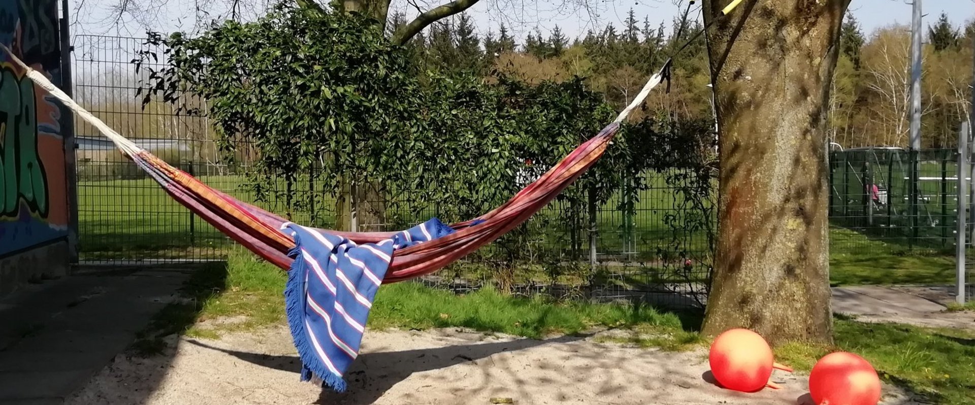 Eine rote Hängematte zwischen zwei Bäumen im Garten der Freizeitstätte Kreyenbrück. Foto: Stadt Oldenburg