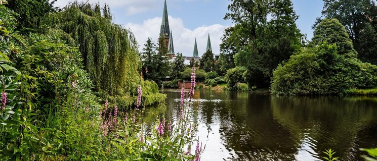 Teich im Schlossgarten mit der Lambertikirche im Hintergrund. Foto: Mittwollen und Gradetchliev