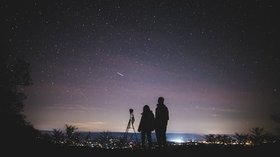 Schattenbild von zwei Personen, die den Sternenhimmel beobachten