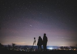 Schattenbild von zwei Personen, die den Sternenhimmel beobachten. Foto: Yuting Gao/Pexels 