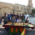 Vorschau: Eine Gruppe Jugendliche steht an einem Verkaufsstand mit Gebäck, im Hintergrund ist ein Stadtmauer aus hellem Stein zu sehen. Foto: Stadt Oldenburg