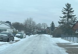 Blick aus dem Führerhaus eines AWB-Fahrzeugs auf eine vereiste Nebenstraße, an der Biotonnen stehen. Foto: Stadt Oldenburg