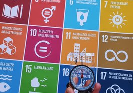 Eine Hand hält einen Kompass, der nach Norden zeigt, über die Kacheln der 17 SDGs. Foto: Stadt Oldenburg