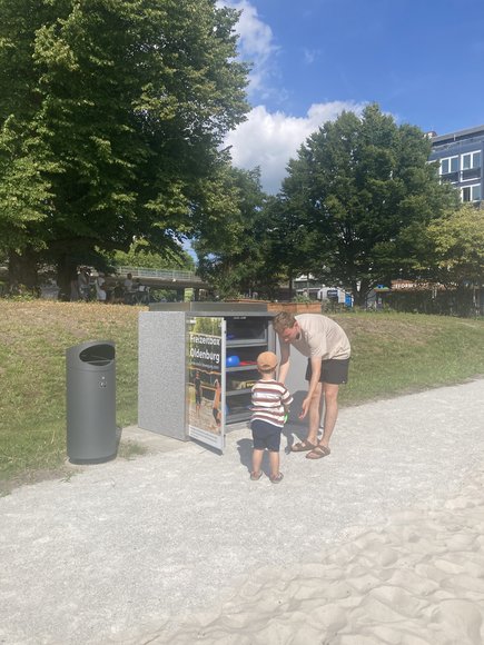 Ein Mann und ein Kind suchen Geräte aus der Sportbox aus. Foto: Stadt Oldenburg