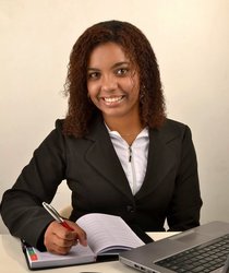 Eine Geschäftsfrau sitzt am Schreibtisch, schreibt etwas in einen Kalender und lächelt in die Kamera. Foto: Daniela_oliiver/Pixabay