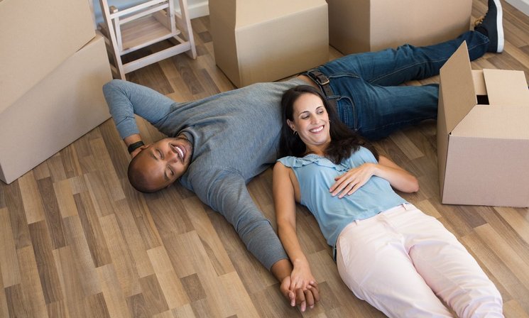 Paar mit Umzugskartons entspannen sich nach dem Umzug in ihrem neuen Heim. Foto: Adobe Stock.