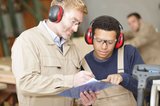 Ein junger Mann und sein Ausbilder besprechen eine anstehende Aufgabe in der Werkstatt. Foto: stafftastic