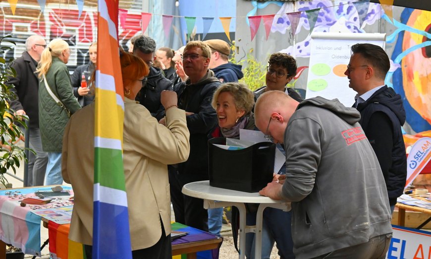 Menschen stehen fröhlich an einem Stehtisch. Foto: Robert Gertzen