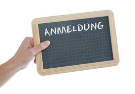 Hand hält Tafel mit dem Wort „Anmeldung“. Foto: Tim Reckmann/Pixelio.de