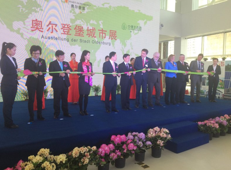 Mitglieder der Oldenburger Delegation und Vertreterinnen und Vertreter des Sino-German Ecoparks stehen auf einer Bühne und durchschneiden ein Band. Foto: Stadt Oldenburg