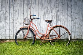 Ein orange-farbenes Fahrrad lehnt an einer Holzwand. Foto: Pexels/alain frechette