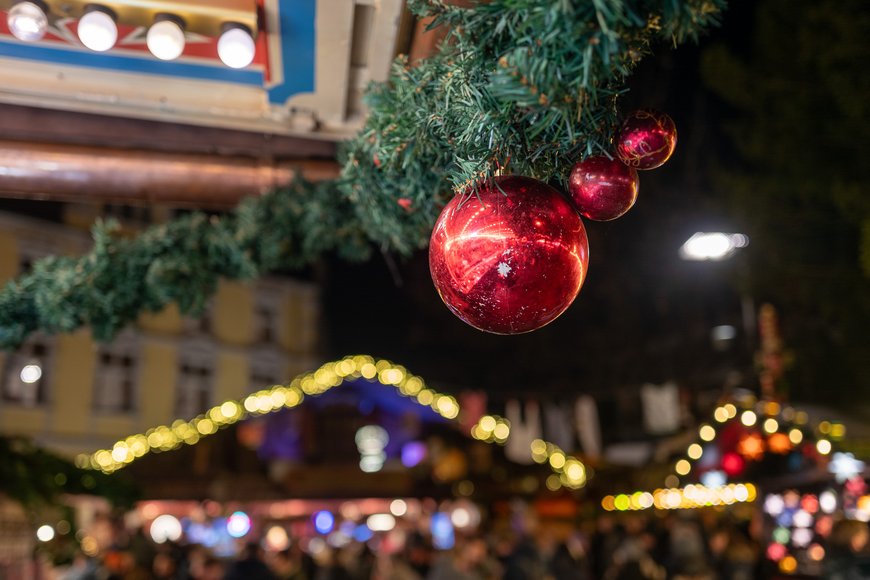 Eine Tannengirlande mit Ständen im Hintergrund auf dem Lamberti-Markt 2025. Foto: Sascha Stüber